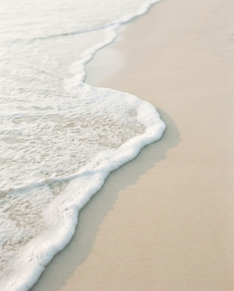 Espuma do mar chegando devagar sobre a areia clara